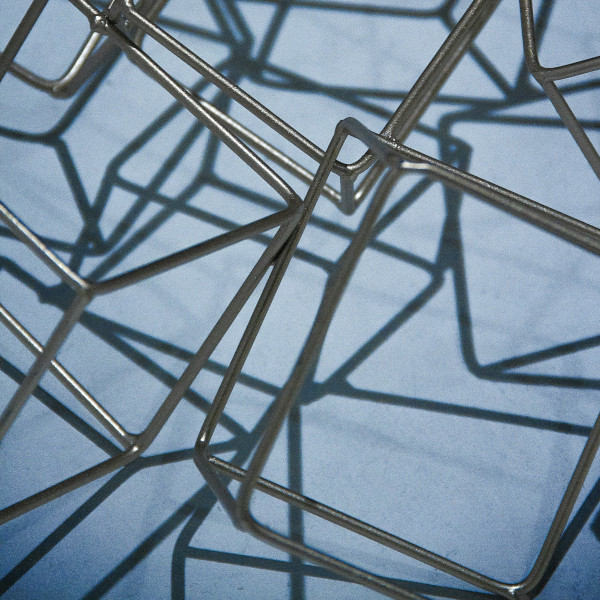 Interlocking grey metal puzzle pieces with shadows beneath, against a blue grey background