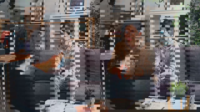 Young person sitting on a sofa talking to an adult whi is taking notes